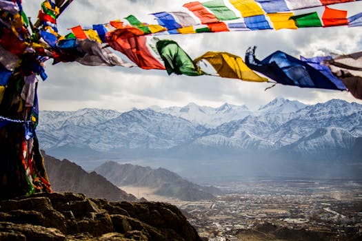 Colorful prayer flags wave over snow-capped peaks and a scenic landscape, creating a stunning natural view.